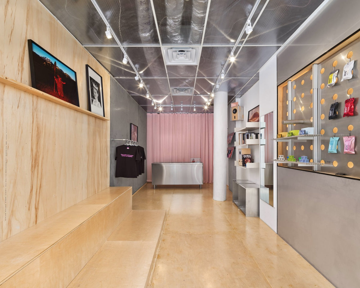 Inside Manual Photo Lab — plywood benches, gallery wall and film shelves